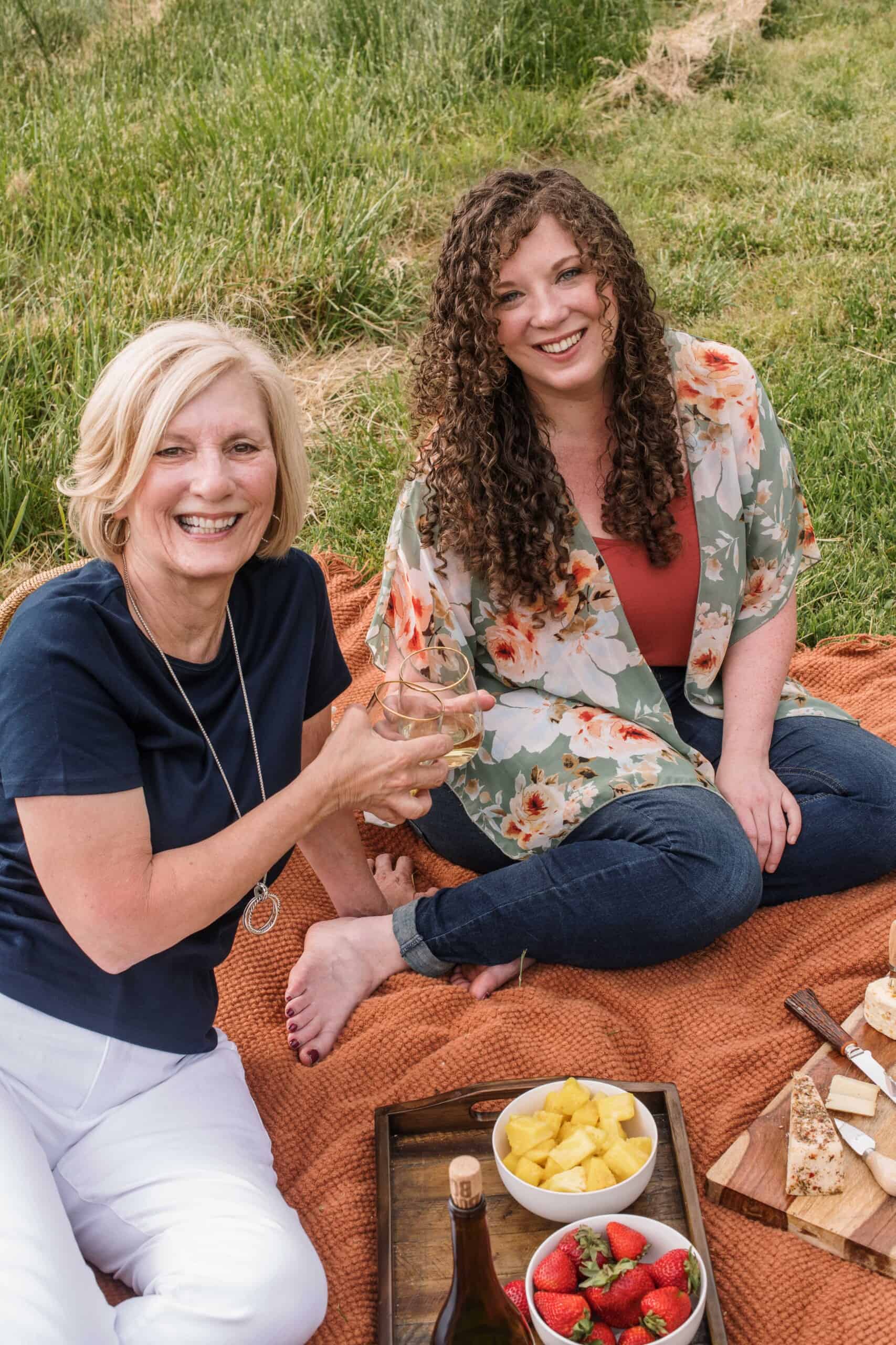 Pam and Sara sitting on blanket with picnic.