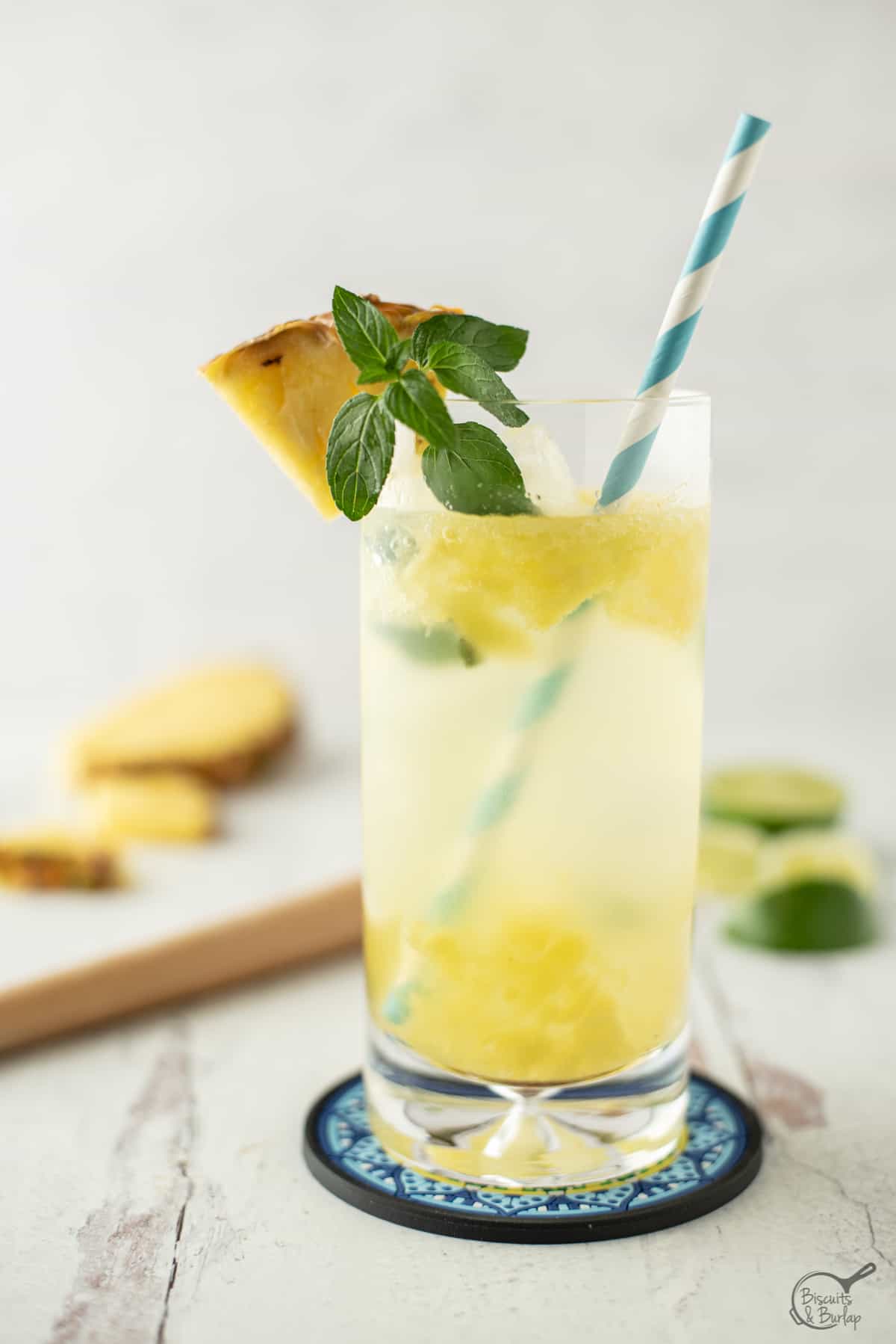 pineapple mojito with blue and white straw and fresh mint and pineapple on the rim