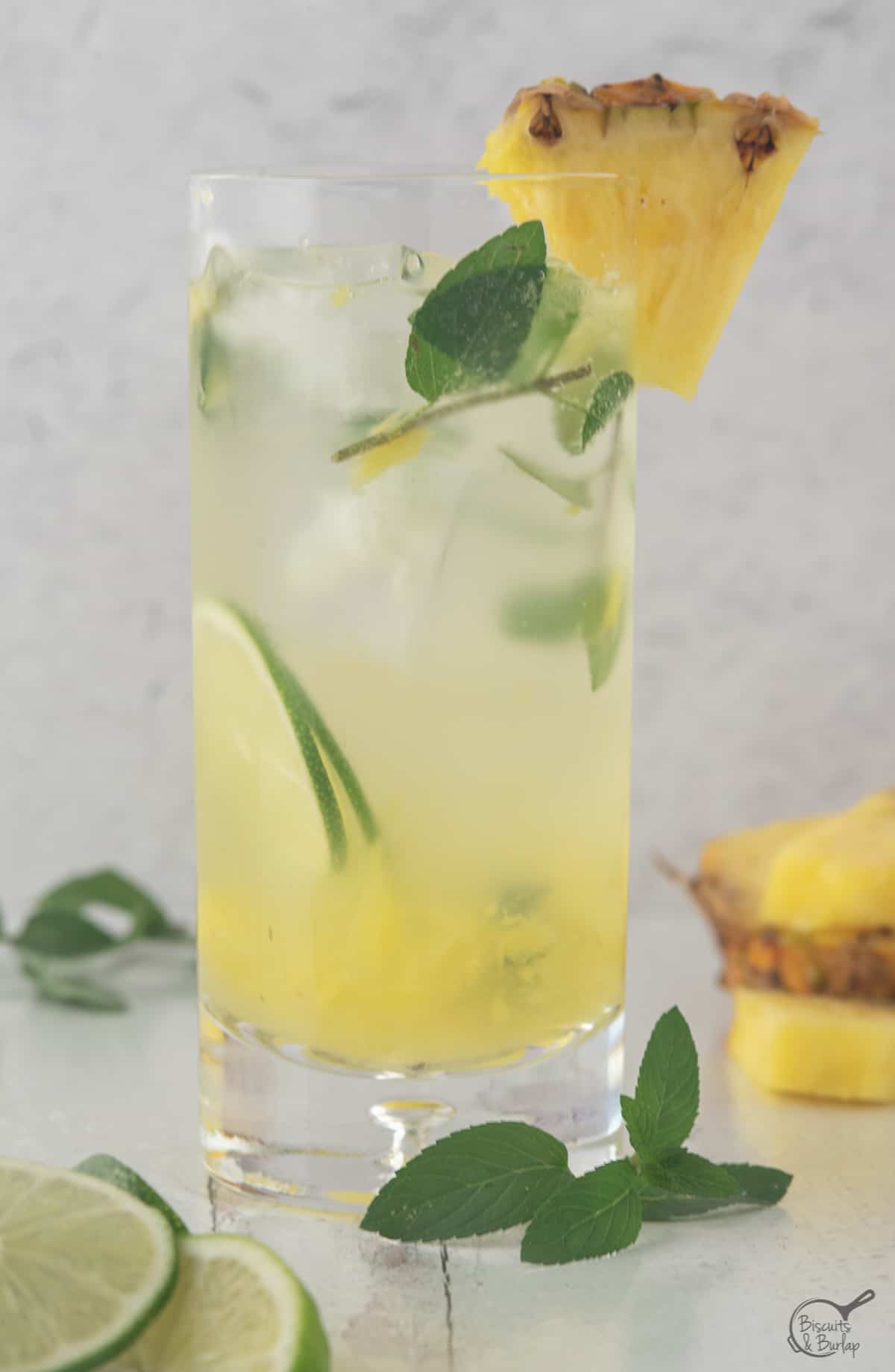 pineapple mojito with blue and white straw and fresh mint and pineapple on the rim