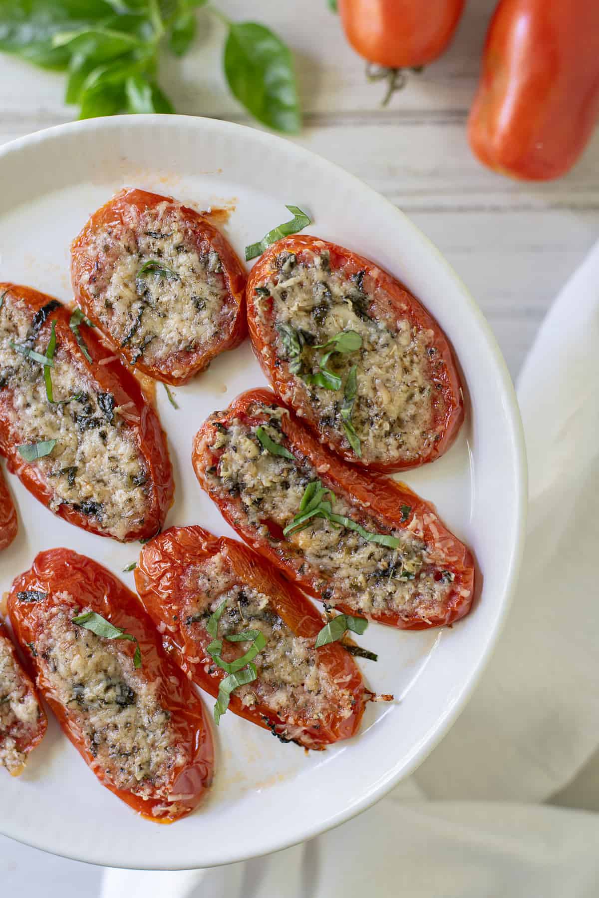 Baked tomato slices with parmesan on white plate with white background