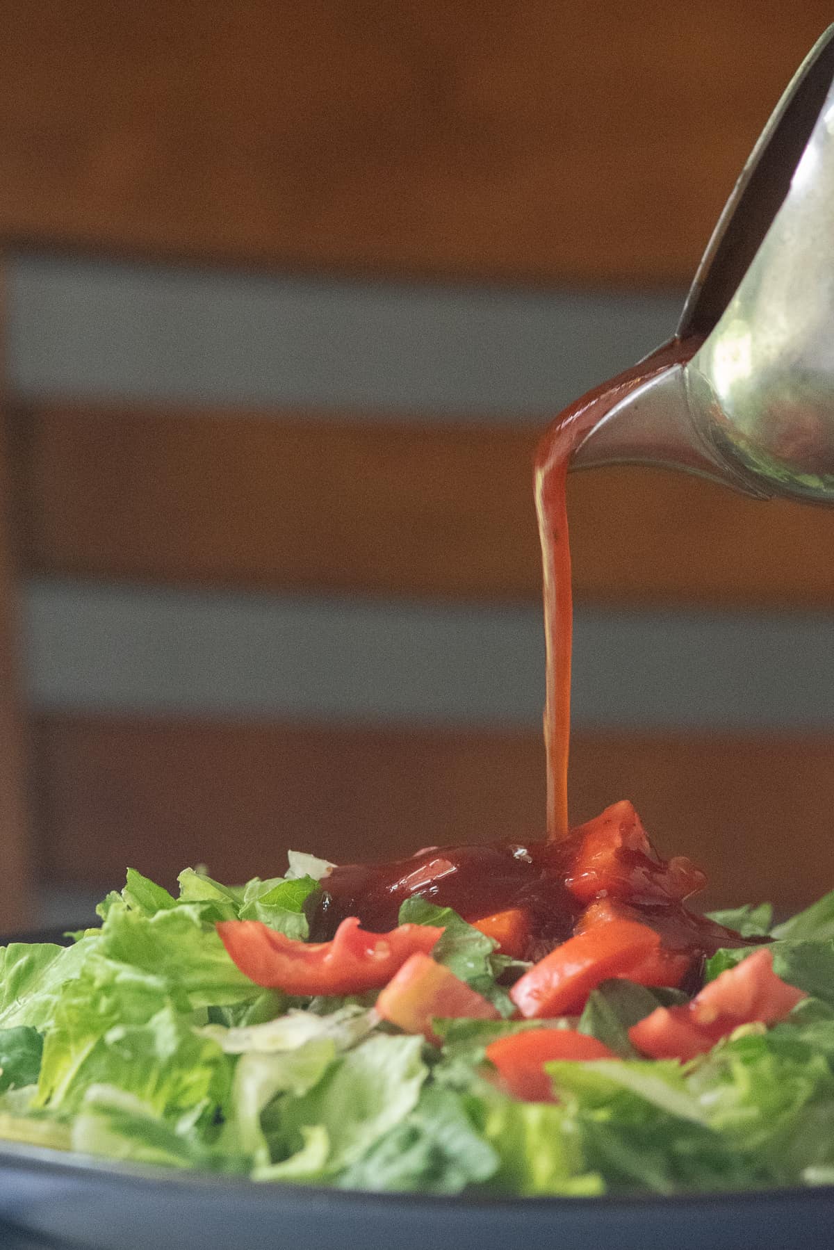 Barbecue Salad Dressing being poured from silver pitcher onto salad