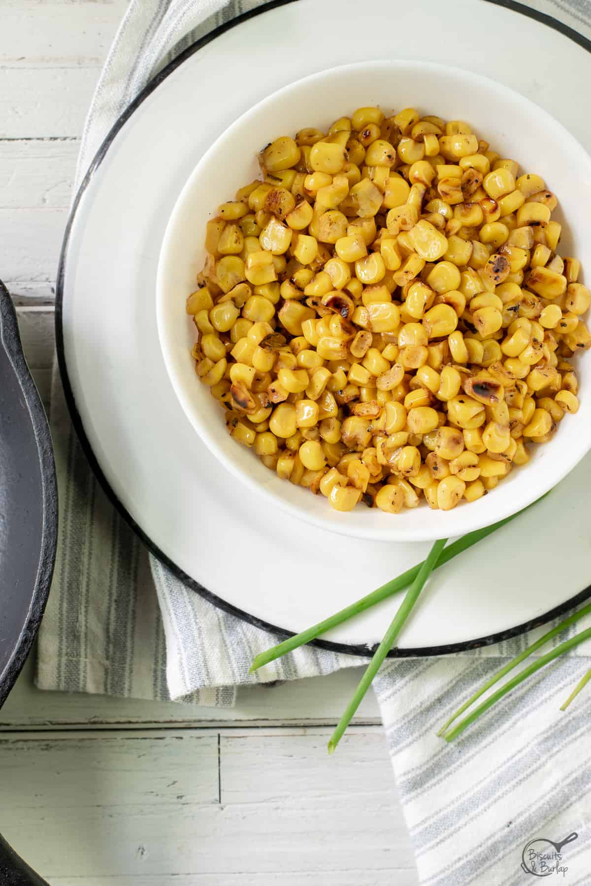 white bowl with charred corn sitting on a plate.