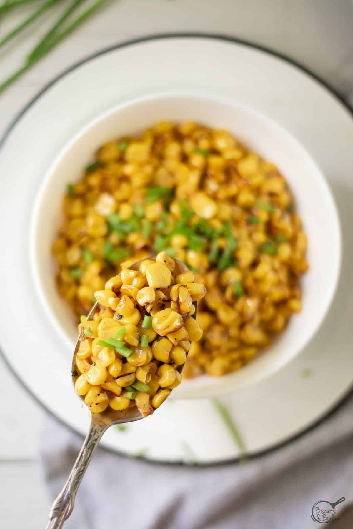 close up spoonful of blackened corn over a full bowl.