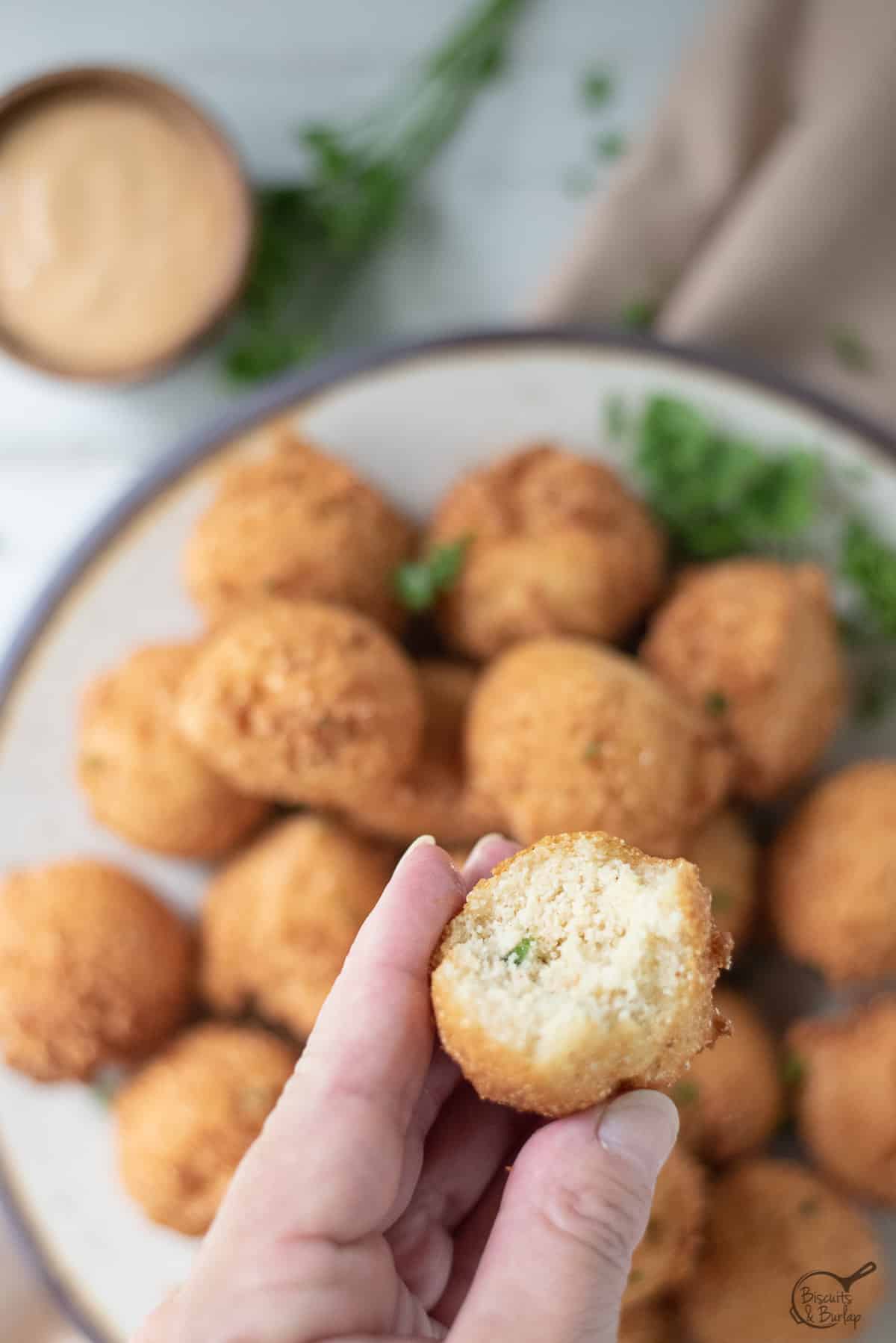 close up of cajun hush puppy over bowl of more. 