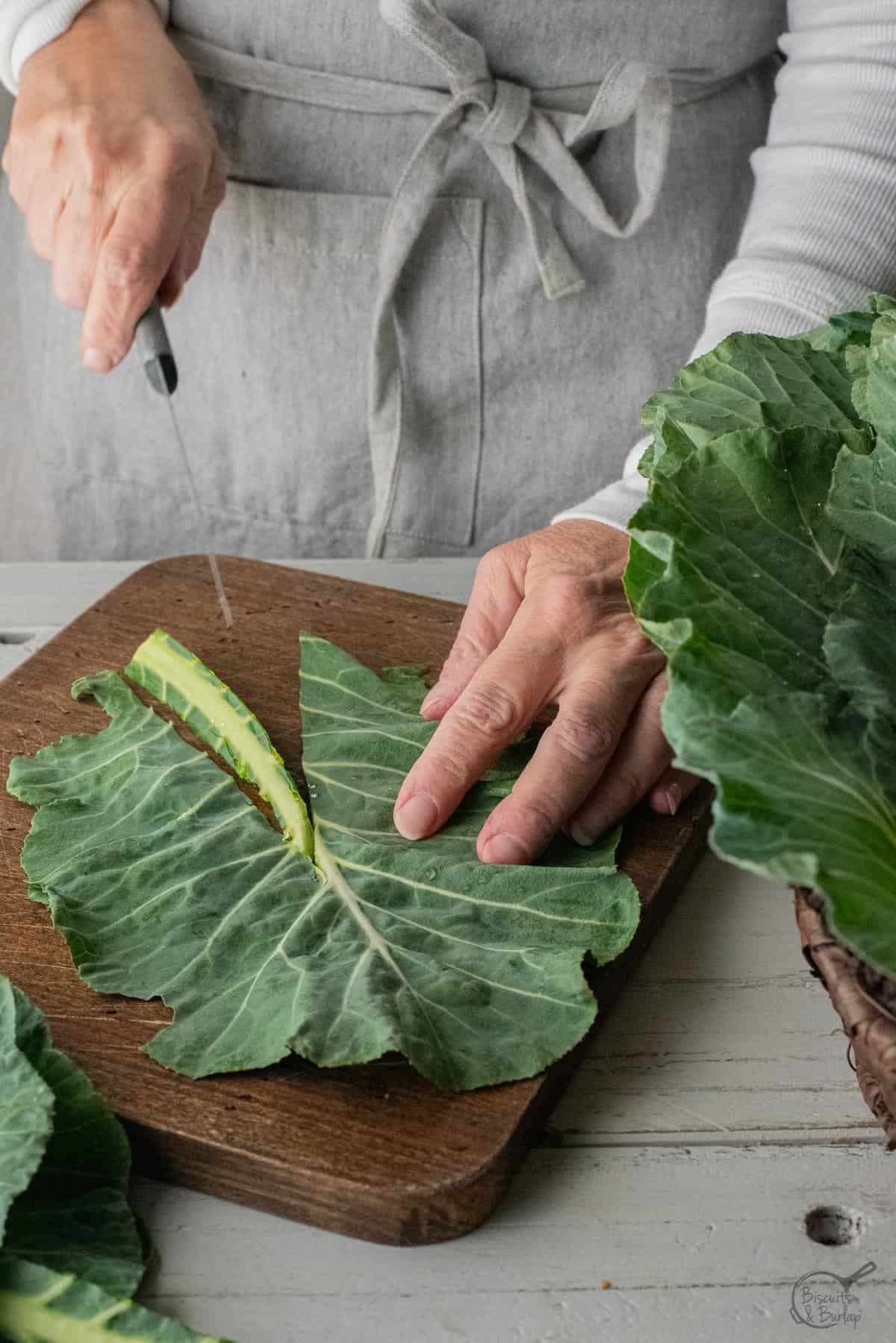 Stem being cut from collard leaf with knife.