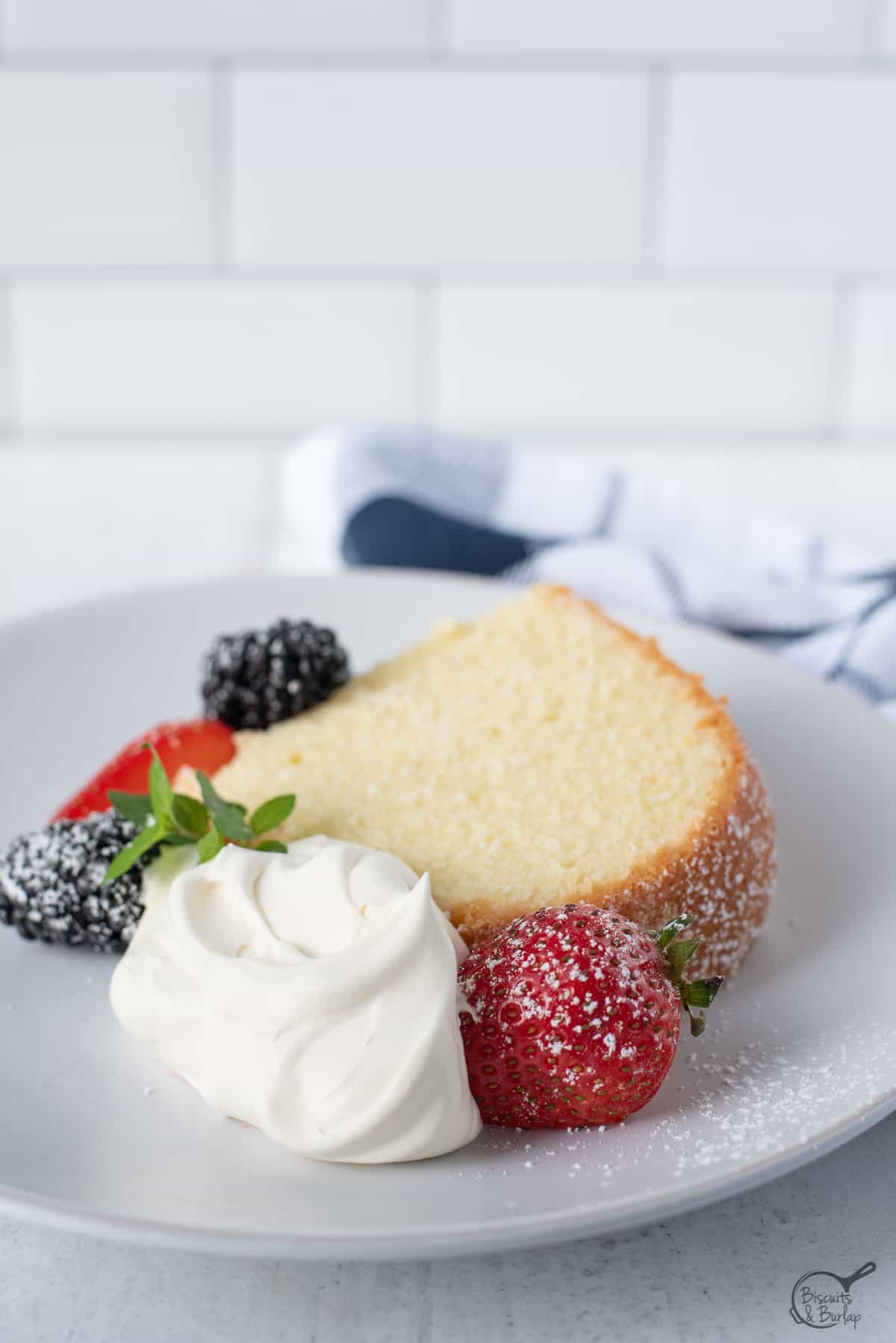 slice of old fashioned cream cheese pound cake with berries and whipped cream.