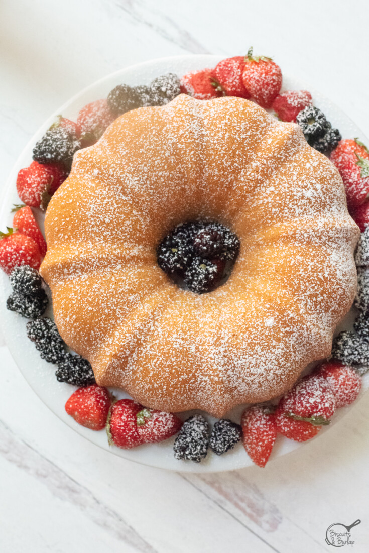 overhead shot of cream cheese pound cake with berries and a dusting of powdered sugar.