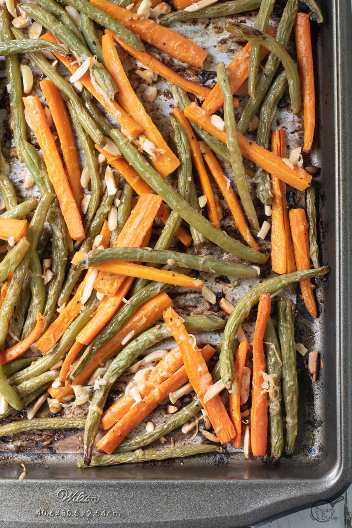 roasted green beans and carrots in baking pan. 