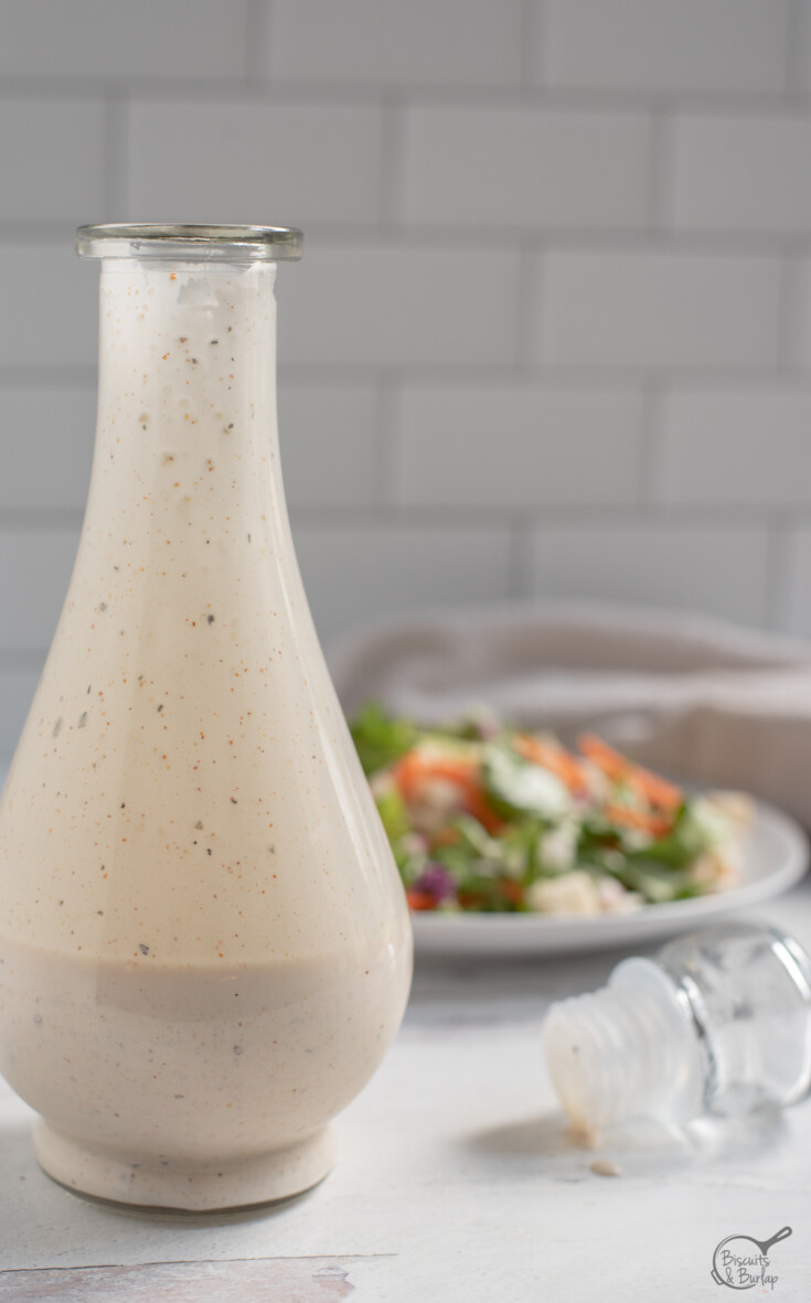 cruet with Cajun Salad dressing and salad behind.