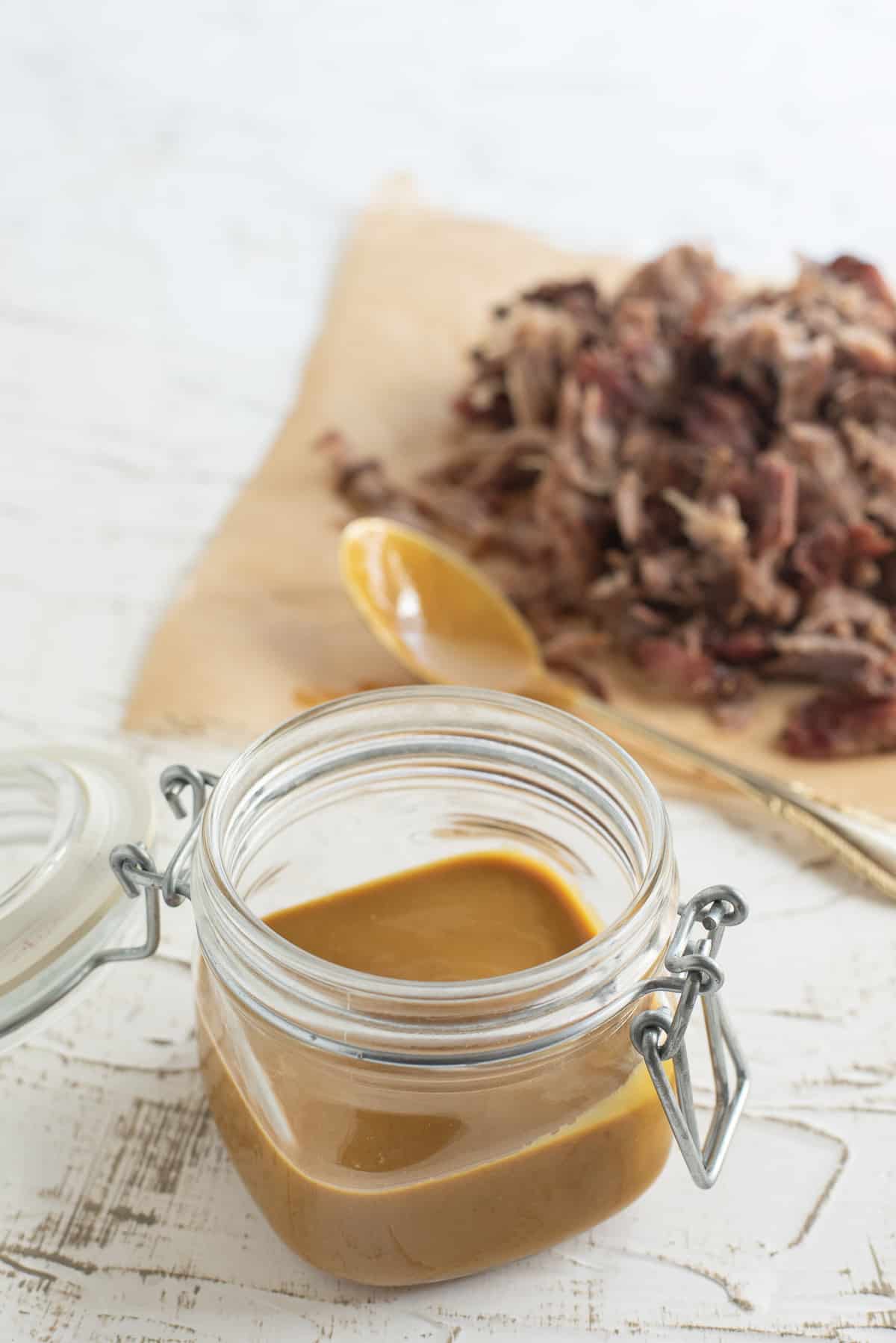 Georgia Mustard BBQ Sauce in a jar, pulled pork and spoon in background