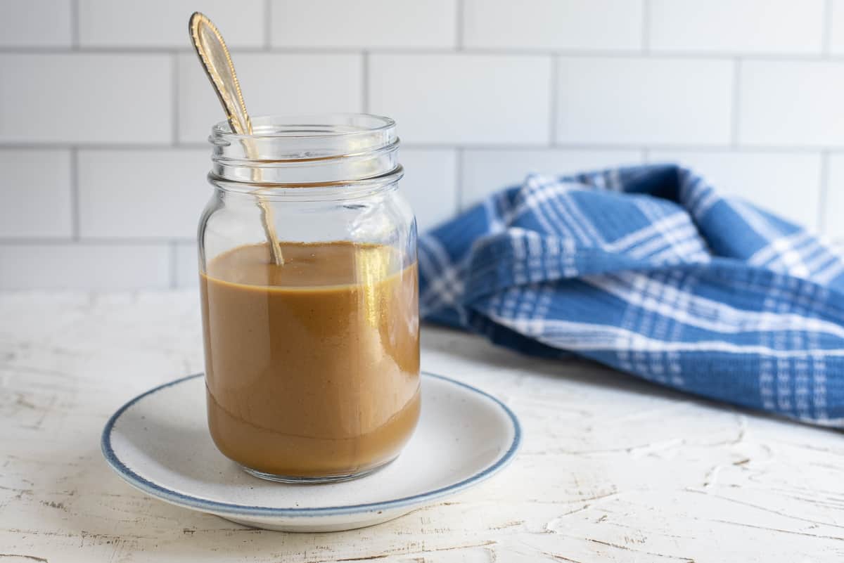 Georgia Mustard BBQ Sauce in a jar with a spoon, blue cloth in background