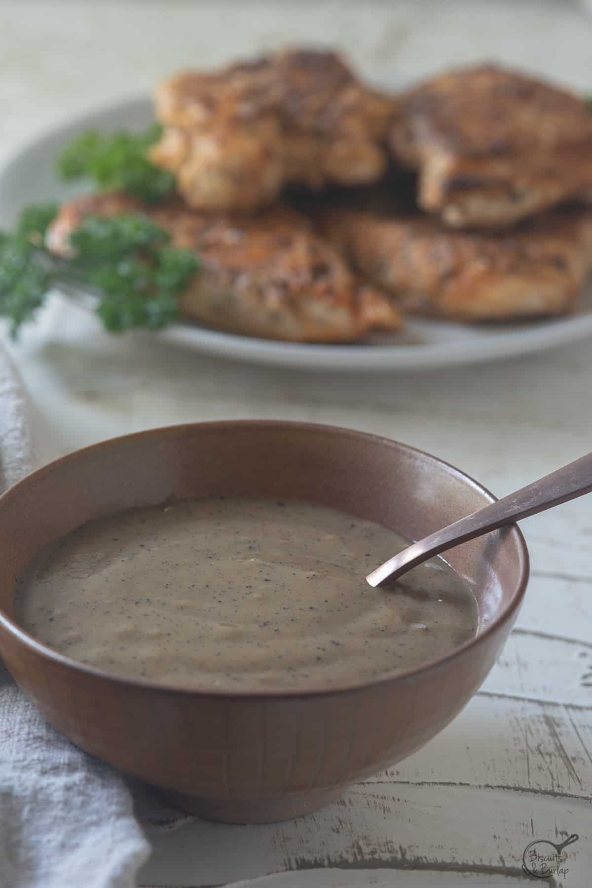 bowl of cajun gravy with chicken behind