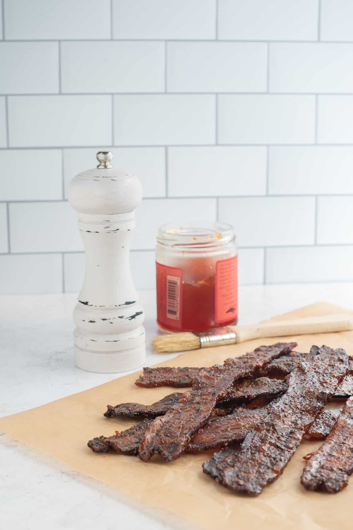 pig candy on paper with pepper jelly and pepper grinder behind.