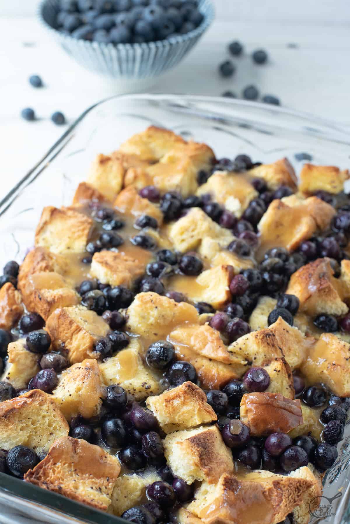 dish with blueberries in back and brioche french toast casserole in front.