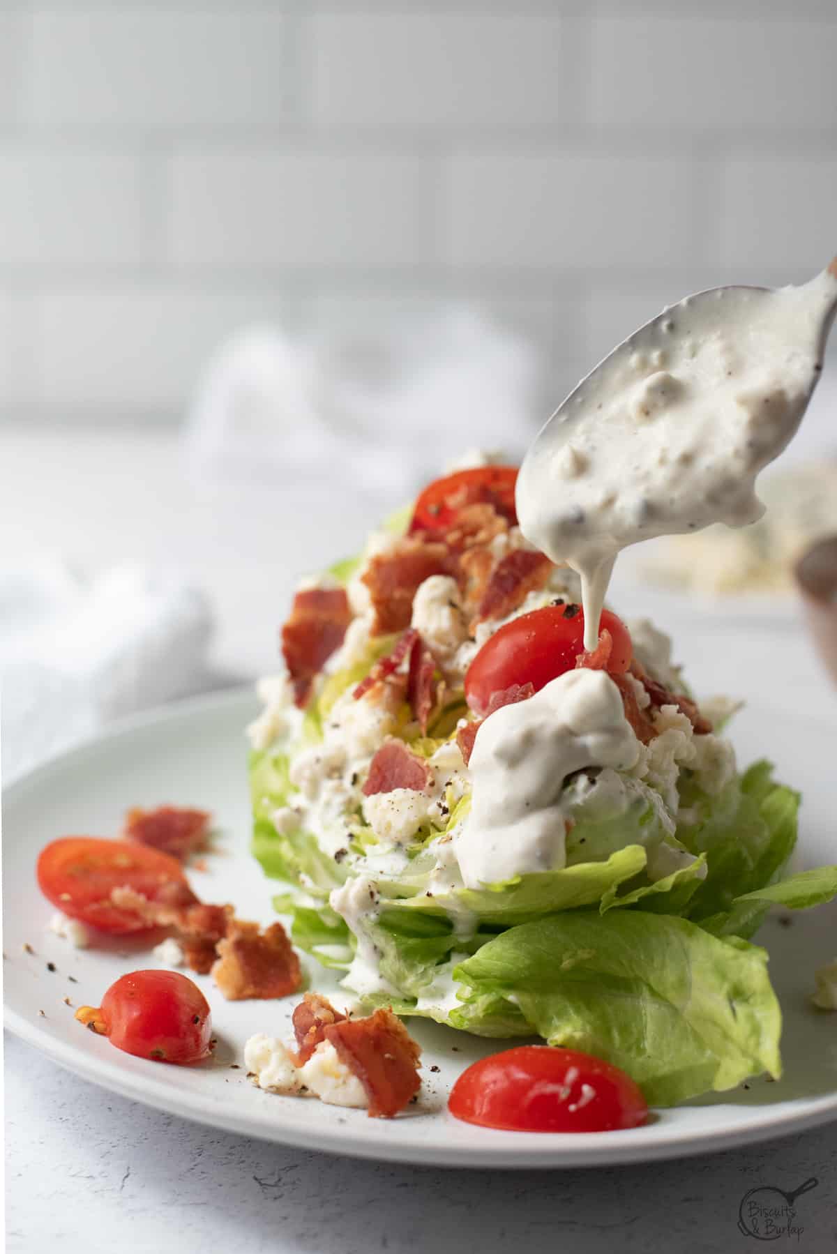 Gorgonzola salad dressing being drizzed on wedge salad.