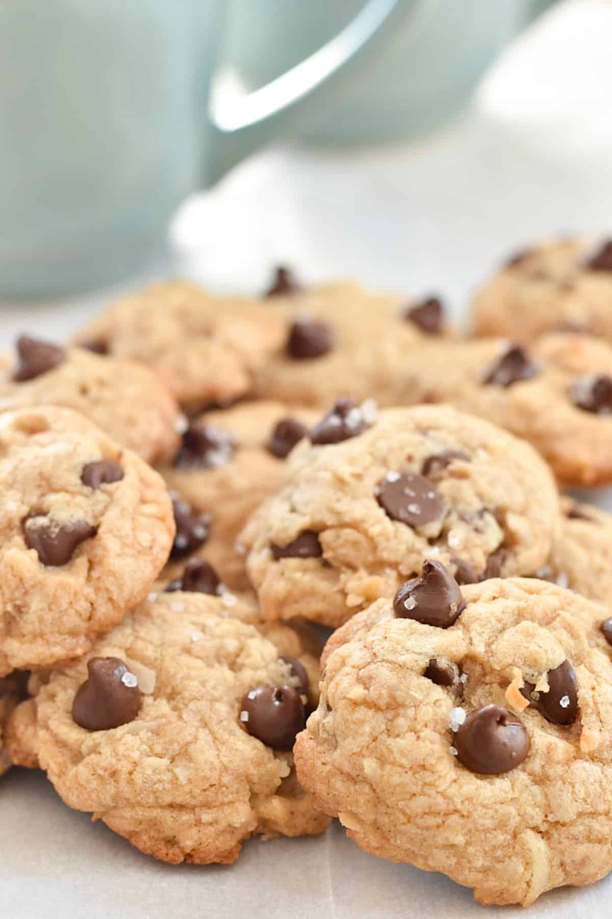 coconut chocolate chip cookies in pile in front of coffee mug