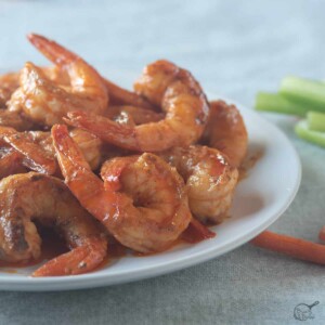 square image of shrimp in buffalo sauce on white plate.