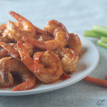 square image of shrimp in buffalo sauce on white plate.