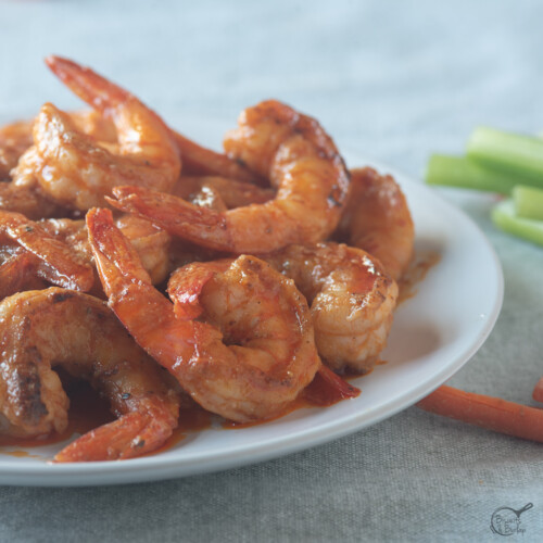 square image of shrimp in buffalo sauce on white plate.