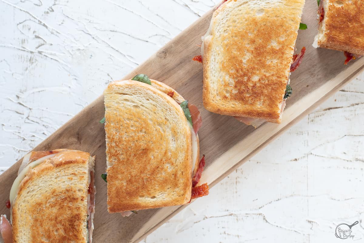 Groumet Grilled cheese, sliced in half on board with white background