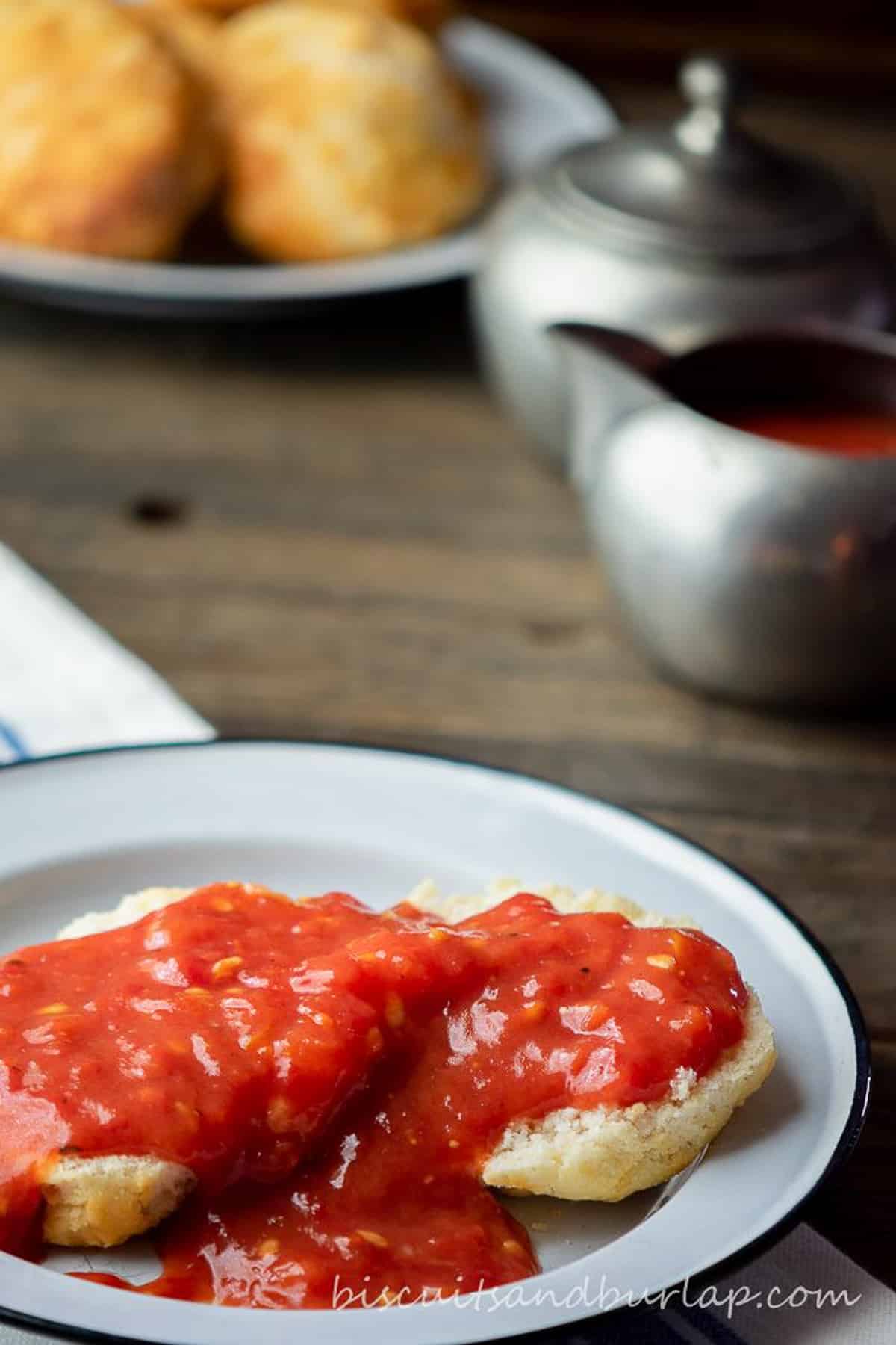 tomato gravy over biscuits on plate.