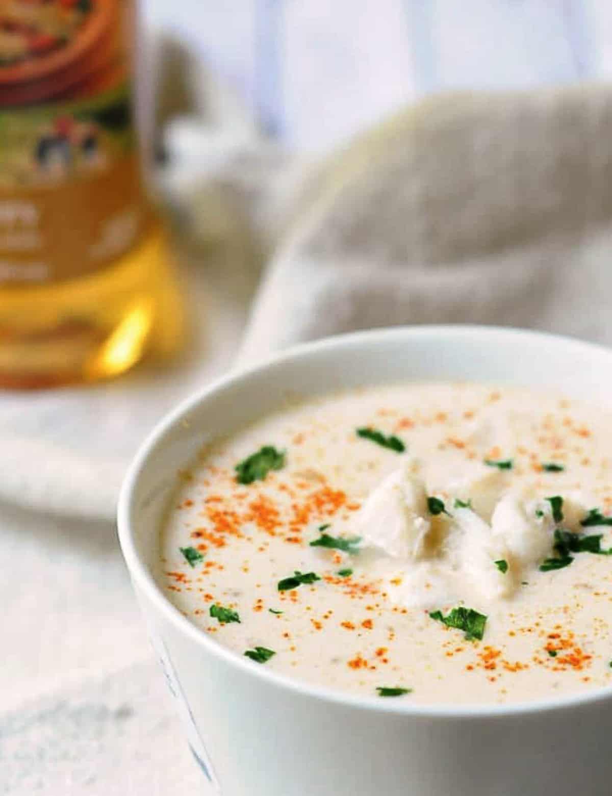 bowl of she crab soup with bottle of sherry behind. 