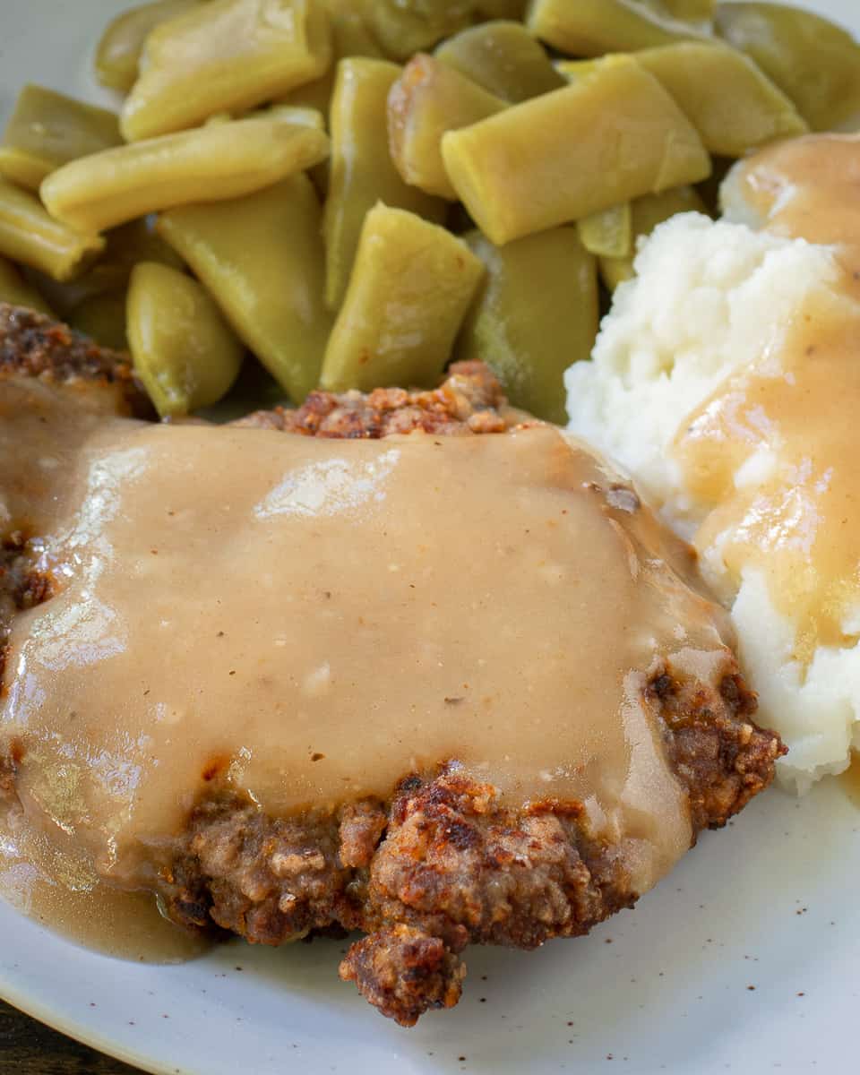 close up of country fried steak on plate with sides. 