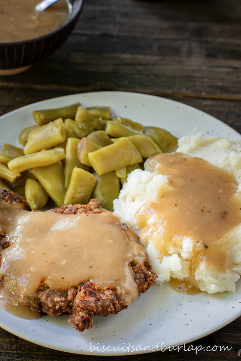 plate with country fried steak, potatoes and green beans.