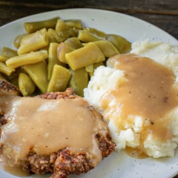 plate with country fried steak, potatoes and green beans.