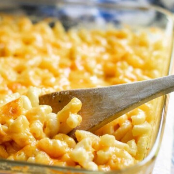 baked macaroni and cheese in dish with wooden spoon.