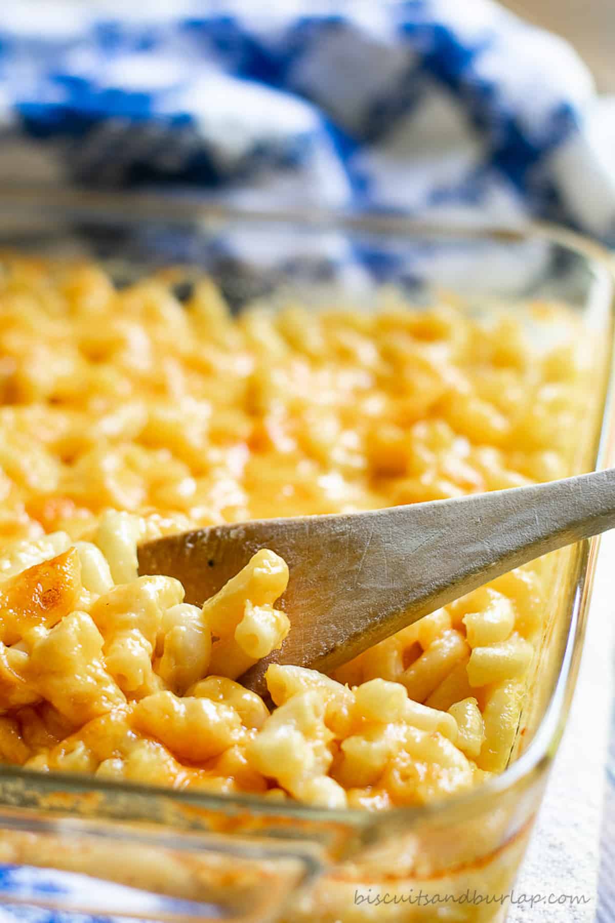 baked macaroni and cheese in dish with wooden spoon.