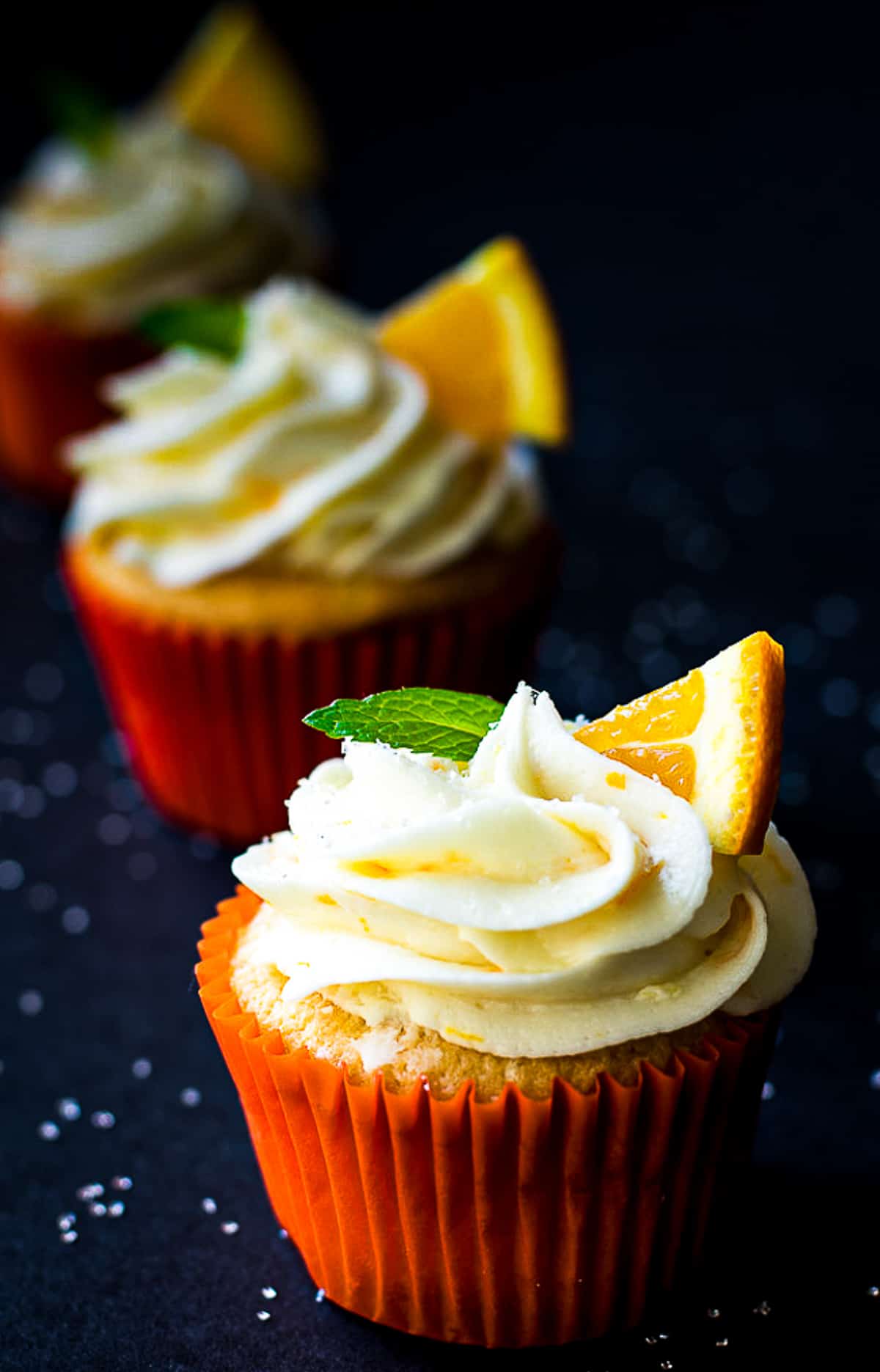 orange cupcake with orange butter cream frosting on black background. 