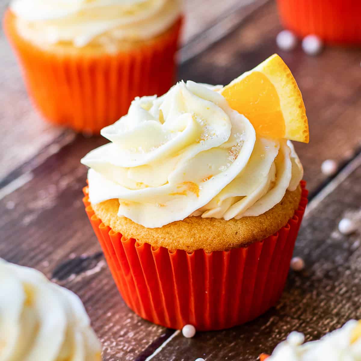 square image or orange cupcake on wood surface.