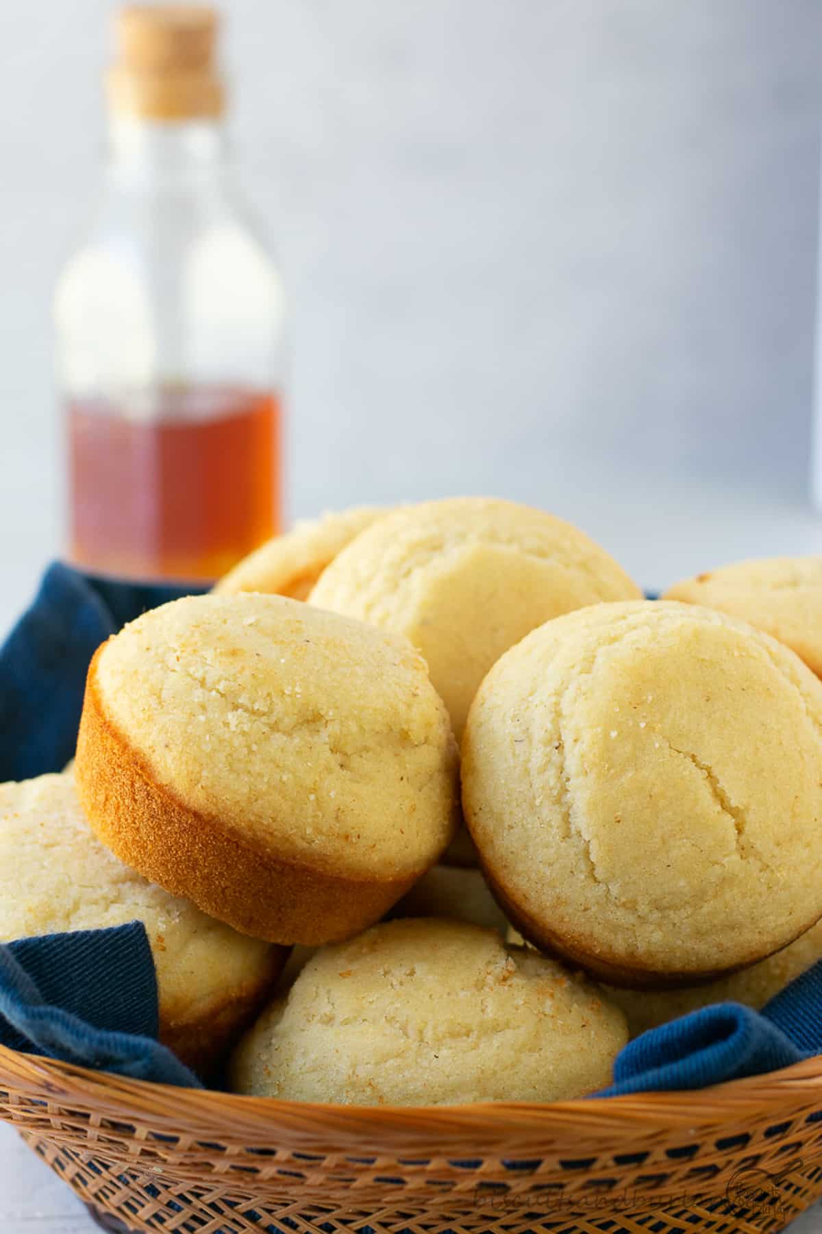 basket of cornbread muffins with honey behind. 