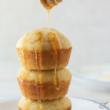 stack of 3 cornbread muffins with honey being drizzled.
