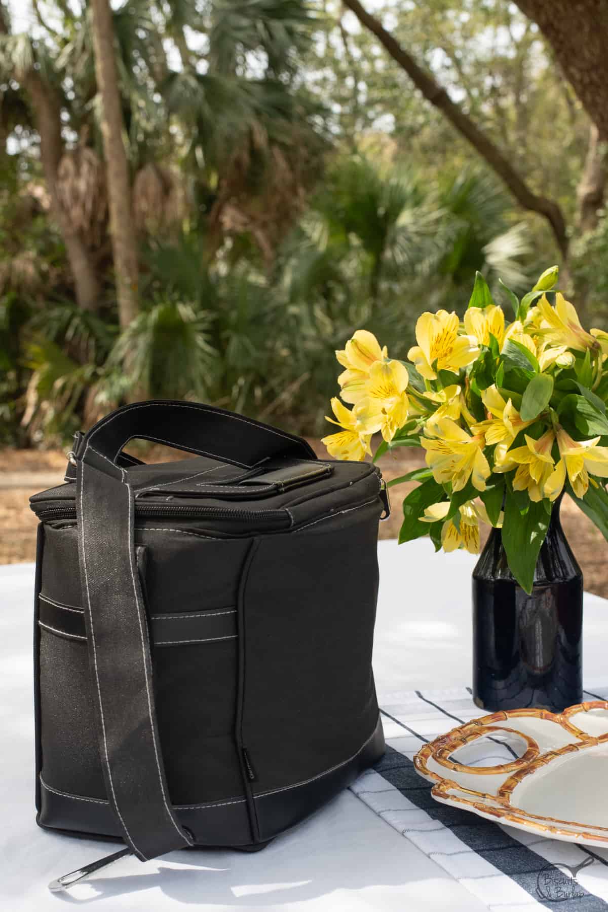 cooler for picnic charcuterie board on table with flowers. 