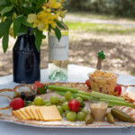 picnic charcuterie board with wine and flowers.