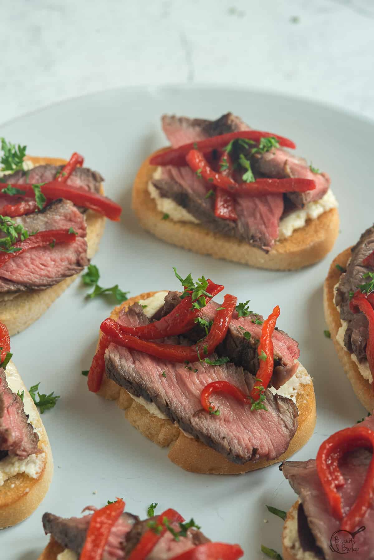 several steak crostini on white plate. 