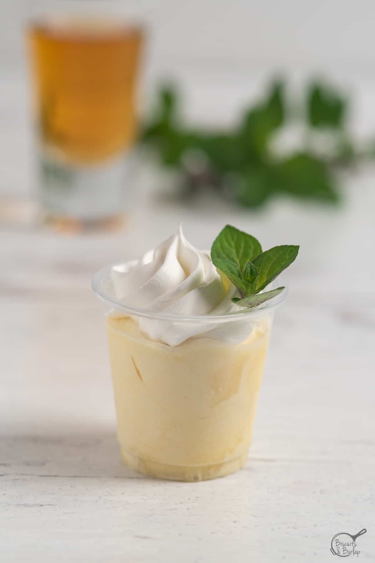 Mint julep pudding shots on white background with bourbon and mint in background