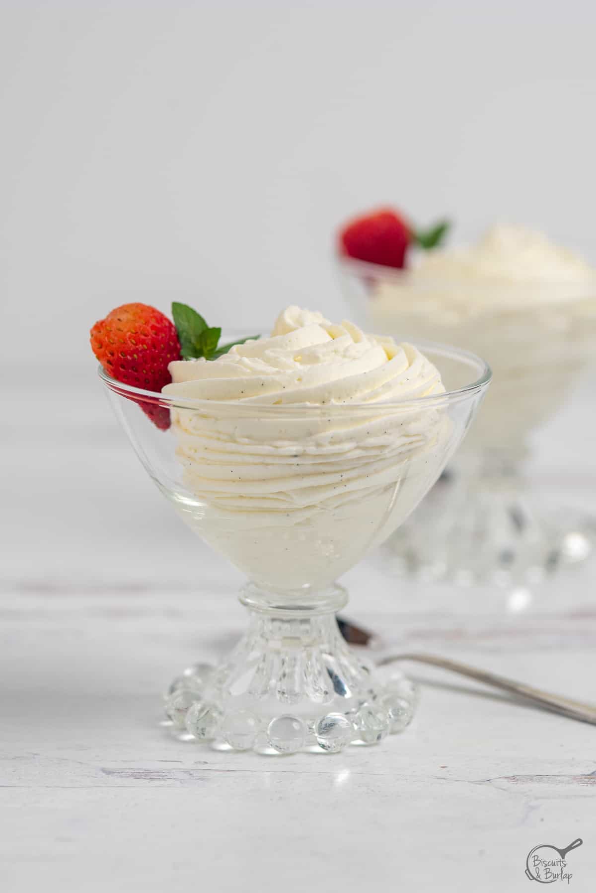 vanilla mousse in glass dish with strawberry garnish. 