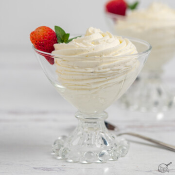two glass dishes of vanilla mousse with strawberry garnish.