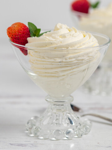 two glass dishes of vanilla mousse with strawberry garnish.