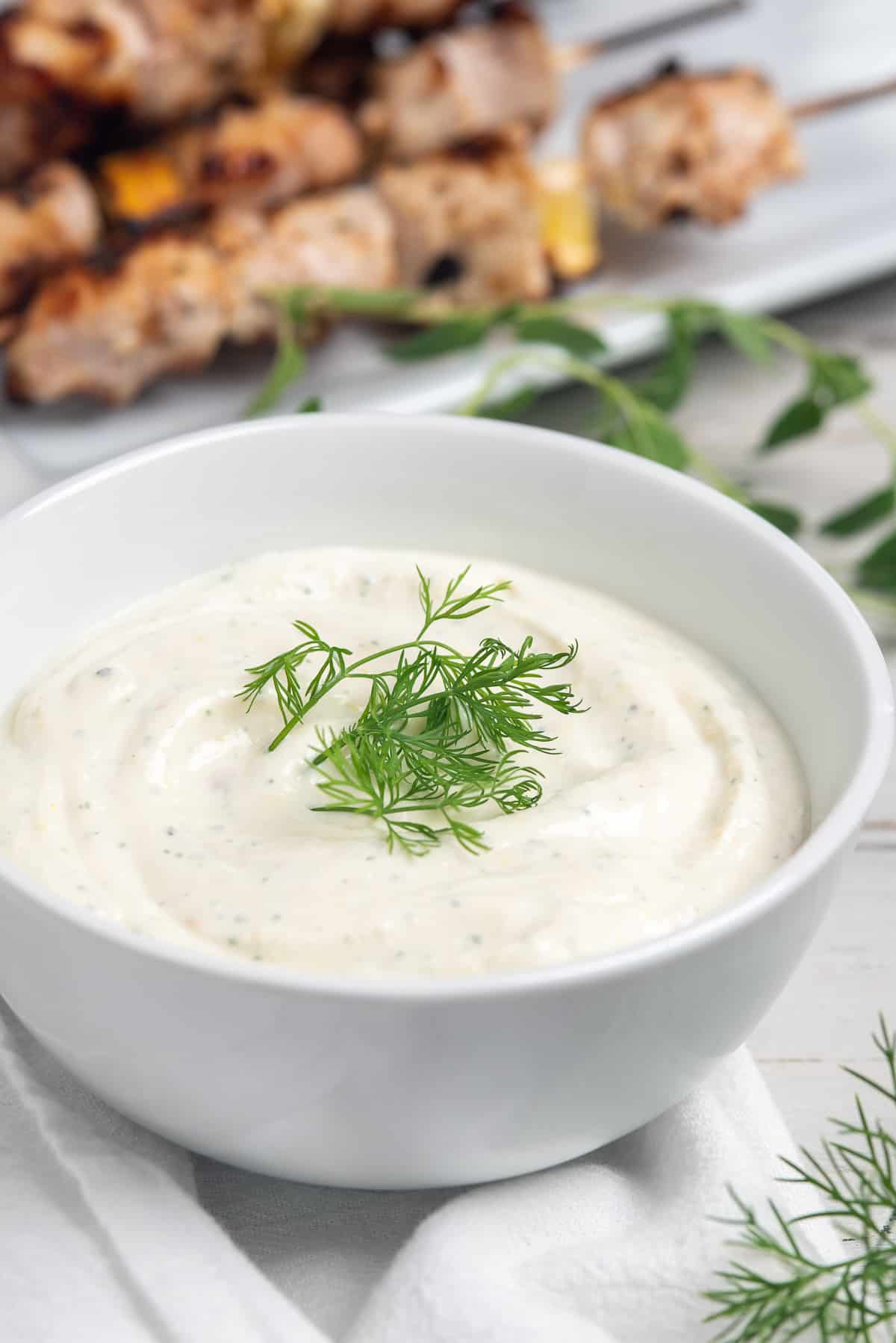 yogurt sauce in bowl with chicken behind. 