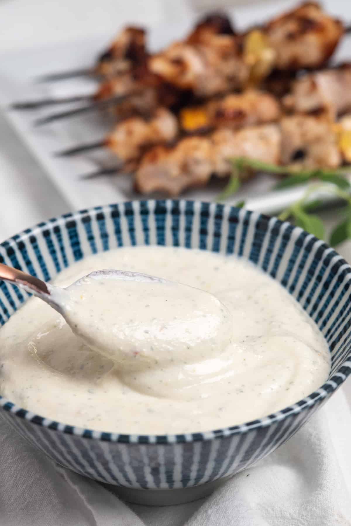 bowl with yogurt sauce for chicken in spoon.
