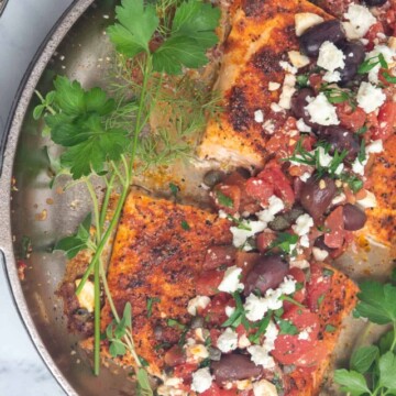 Salmon fillets in skillet with herbs and greek topping.