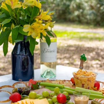 picnic charcuterie board with wine and flowers.