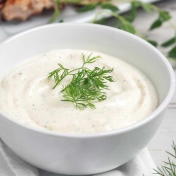 yogurt sauce in bowl with chicken behind.