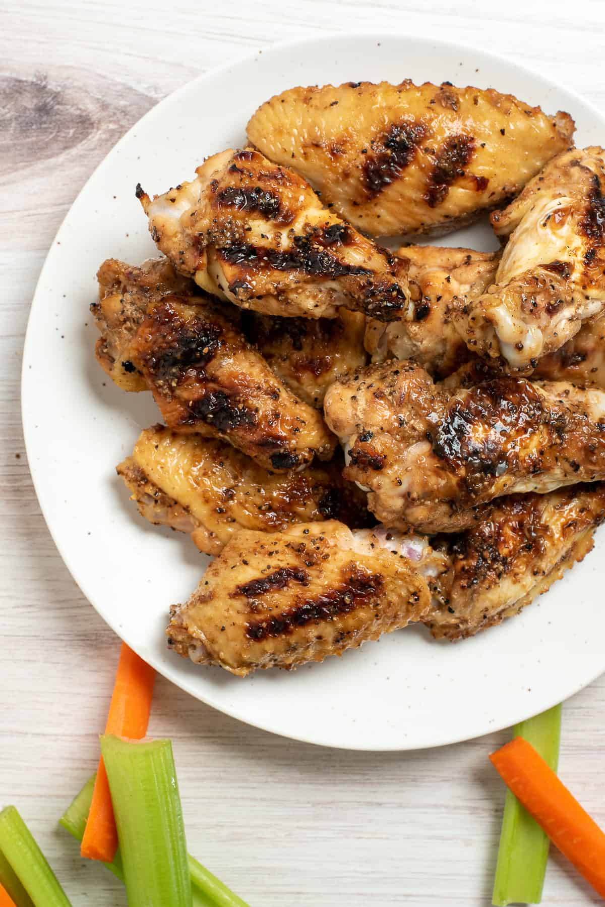 honey lemon pepper wings on plate with carrots and celery. 