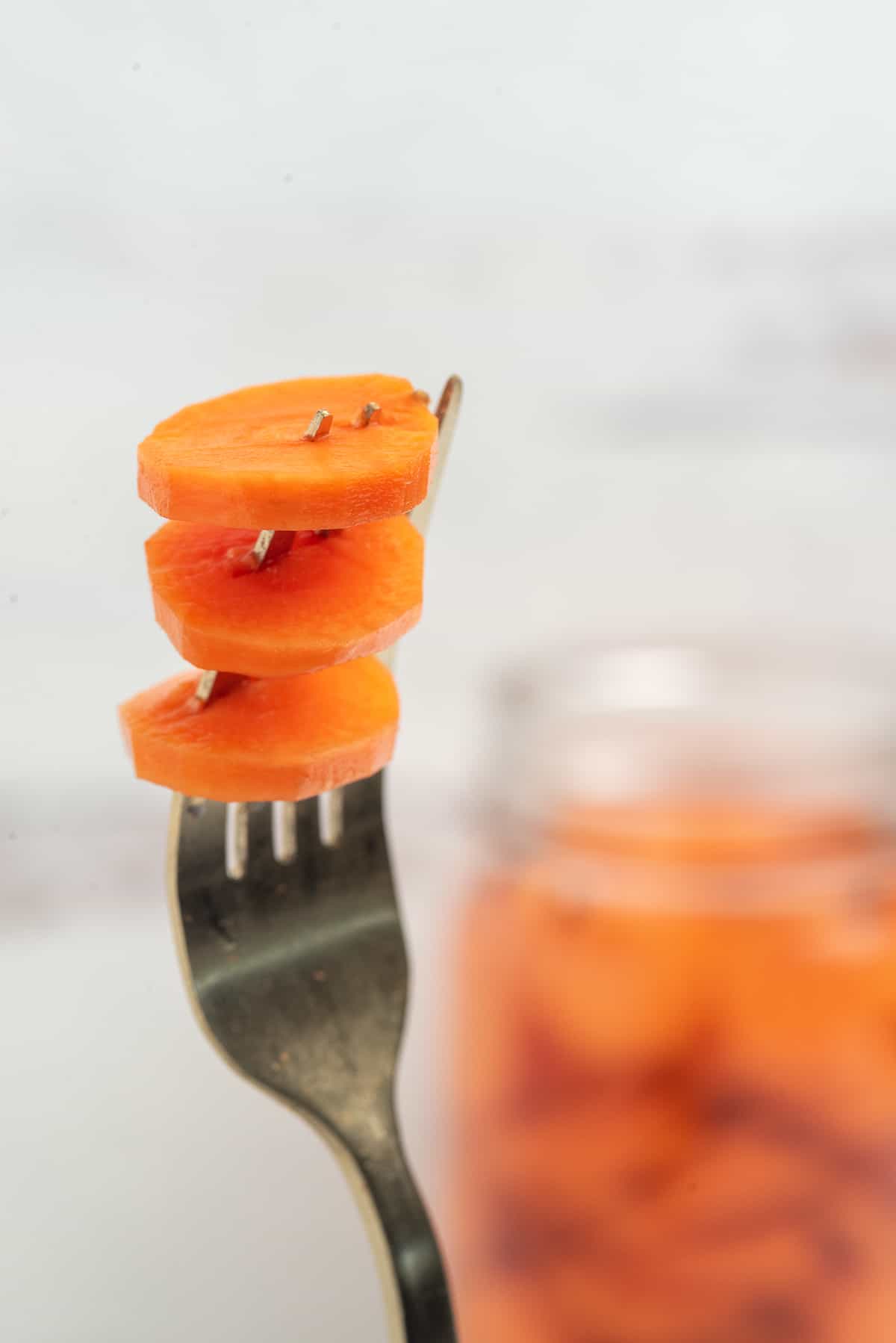 3 pickled carrot slices on a fork. 