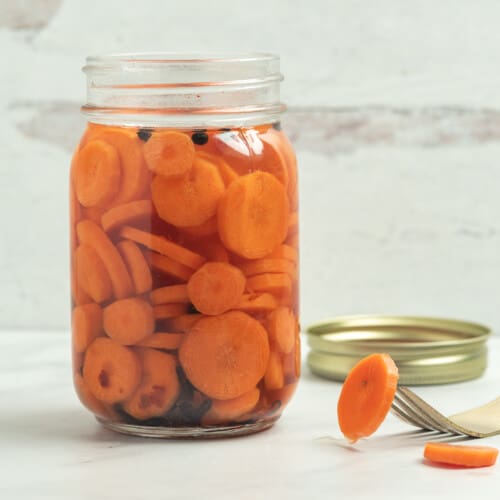 open jar of carrots in pickling solution.